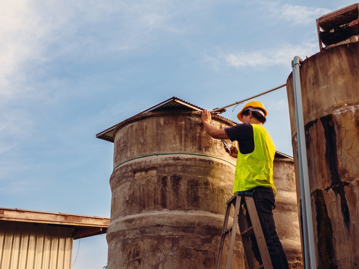 Professional engineers inspecting and cleaning water tanks at height